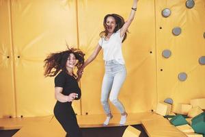 The company is a young woman who has fun with soft blocks on a children's playground in a trampoline center. photo