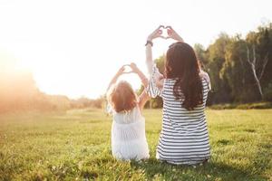 Portrait of a mother and her girl make up her heart in the park. photo