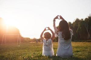 Portrait of a mother and her girl make up her heart in the park. photo