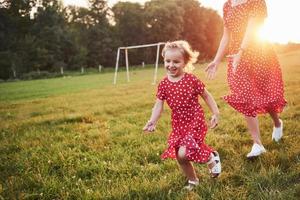 madre juega con su hija en la calle en el parque al atardecer foto