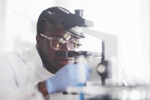 The scientist works with a microscope in a laboratory conducting experiments and formulas. photo