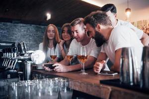 Leisure and communication concept. Group of happy smiling friends enjoying drinks and talking at bar or pub photo