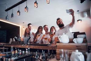 concepto de ocio y comunicación. Grupo de amigos sonrientes felices disfrutando de bebidas y hablando en el bar o pub foto