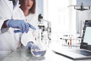Los laboratorios de laboratorio realizan experimentos en un laboratorio químico en matraces transparentes. fórmulas de salida