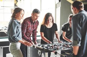 Smiling young people playing table football while indoors photo