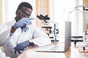 un trabajador afroamericano trabaja en un laboratorio realizando experimentos. foto