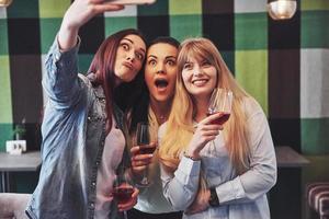 Picture presenting happy group of friends with red wine taking selfie photo