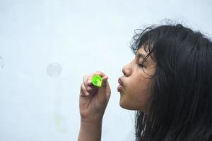 A girl holding a bubble maker and blowing them out. photo