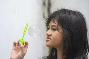 una niña que sostiene una máquina de hacer burbujas y las sopla. foto