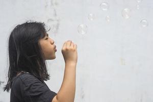 una niña que sostiene una máquina de hacer burbujas y las sopla. foto