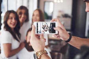 Blur portrait of blissful young best friends with hands holding phone on foreground photo