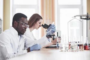 Los científicos trabajan en estrecha colaboración con el microscopio en el laboratorio mediante la realización de experimentos y análisis. foto