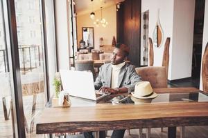 Portrait of african american man sitting at a cafe and working on a laptop photo