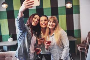 Imagen que presenta feliz grupo de amigos con vino tinto tomando selfie foto