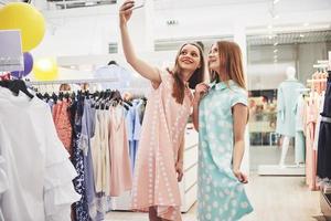 buen dia para ir de compras. dos mejores amigas hacen un sephi en una tienda de ropa foto