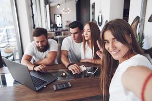 un grupo de jóvenes con gadgets y una computadora portátil organizan una lluvia de ideas y se comunican entre sí. el concepto de desarrollar una empresa joven foto