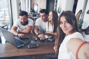 un grupo de jóvenes con gadgets y una computadora portátil organizan una lluvia de ideas y se comunican entre sí. el concepto de desarrollar una empresa joven foto