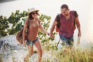 dos turistas masculinos y femeninos con mochilas suben a la cima de la montaña y disfrutan del amanecer. concepto de vacaciones de aventura de estilo de vida de viaje foto