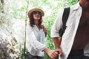 dos excursionistas con mochilas en la espalda en la naturaleza. hombre y mujer tomados de la mano mientras caminan en un día de verano