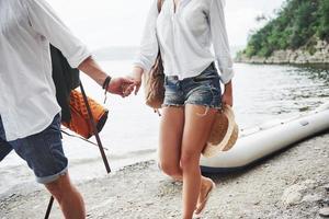Cute young and couple on river background. A guy and a girl with backpacks are traveling by boat. Traveler summer concept photo