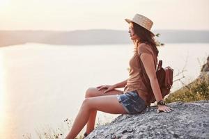 mujer joven turista en la parte superior del montaje y mirando un hermoso paisaje de la bahía. Senderismo mujer con mochila relajándose en la cima del acantilado