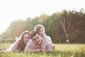 familia feliz, padre de madre e hija de bebé en la naturaleza al atardecer foto