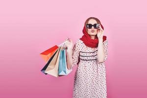 Portrait of young happy smiling woman with shopping bags on the pink Background photo