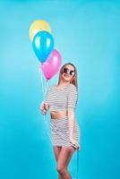 Happy smiling woman is looking on an air colorful balloons having fun over a blue background photo