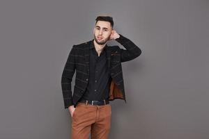 Successful young businessman in a brown suit with a lovely genuine smile posing against a dark grey background with copy space photo