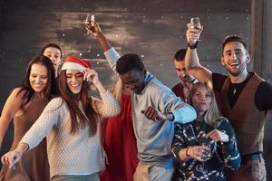 Party with friends. They love Christmas. Group of cheerful young people carrying sparklers and champagne flutes dancing in new year party and looking happy. Concepts about togetherness lifestyle photo