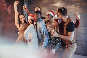 Party with friends. They love Christmas. Group of cheerful young people carrying sparklers and champagne flutes dancing in new year party and looking happy. Concepts about togetherness lifestyle photo