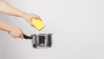 Pot cleaning. Man hand on white background cleaning the non stick pot photo