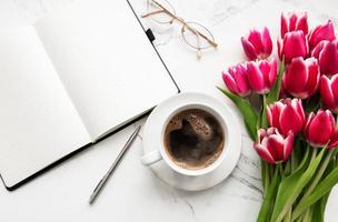 cuaderno, taza de café y tulipanes rosas foto