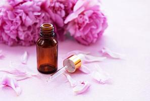 Aromatherapy essentials oils and pink peonies photo