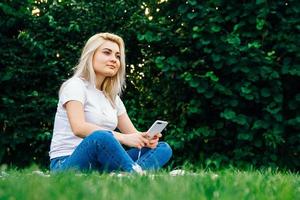 mujer en auriculares y smartphone sobre hierba verde foto