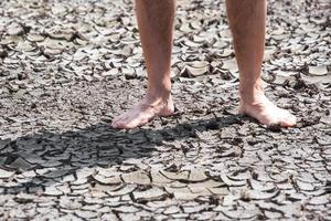 bare feet of a person on dry soil without plants close up photo