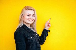Woman lifting a finger up posing on yellow background photo