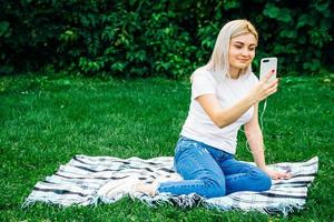 mujer en auriculares y smartphone sobre hierba verde foto
