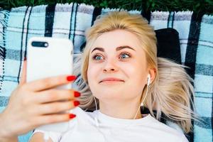 mujer en auriculares y smartphone en manos mintiendo