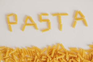 Inscription pasta on white background and spiral pasta photo