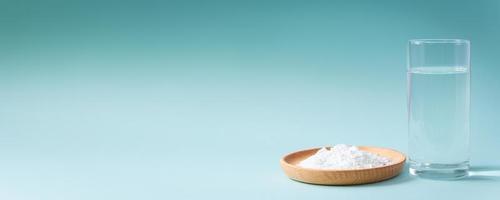 Collagen powder and glass of pure water on blue background photo