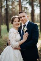 the bride and groom are walking in a pine forest photo