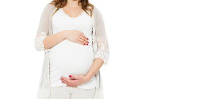Pregnant woman holds hands on belly on a white background. Pregnancy, maternity, preparation and expectation concept. Close-up, copy space, indoors. Beautiful tender mood photo of pregnancy.