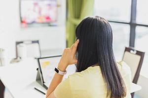 Vista posterior de la mujer discutiendo con el cliente sobre el trabajo del teléfono celular desde casa. foto