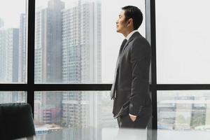 Businessman standing next to window looking out side view.