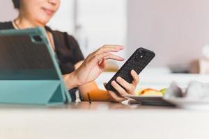 mujer trabaja en casa y usa un teléfono inteligente y una computadora de bloc de notas. foto