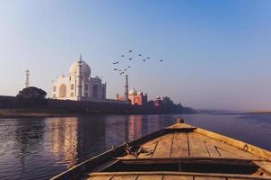 Sunrise over Taj Mahal view from wooden boat in Yamuna River.