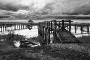 Black and white footbridge into the lake with cloud scape photo
