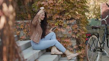 jolie jeune femme avec téléphone portable boire du café pour aller à vélo le jour de l'automne video