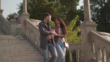 Pretty young couple smiling and talking while strolling down outdoor stairs on autumn day video